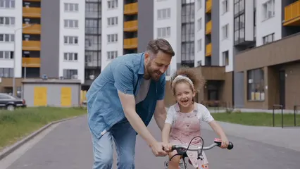 Horizontal video: Father assisting her daughter riding a bike 8747597. Duration: 7 seconds. Resolution: 3840x2160