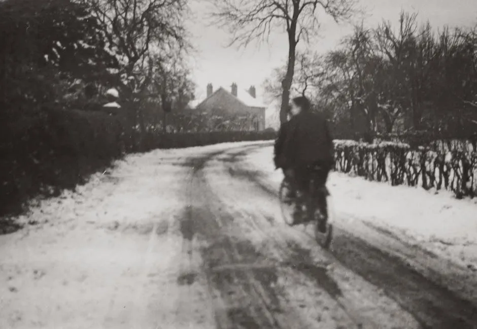 Grayscale Photography of Boys Riding a Bicycle On A Snow Covered Road