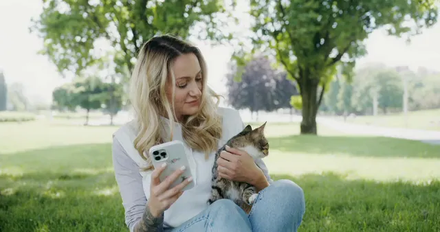 Horizontal video: Woman holding a cat while using her phone 8434053. Duration: 10 seconds. Resolution: 4096x2160
