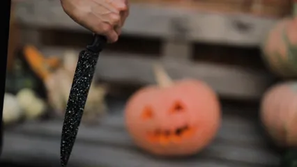 Horizontal video: A person holding a knife in front of a halloween pumpkin 5422492. Duration: 9 seconds. Resolution: 1920x1080