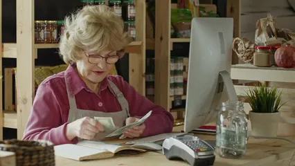 Horizontal video: A woman busy computing money behind the counter 3192364. Duration: 26 seconds. Resolution: 3840x2160