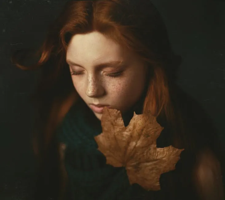 A Woman with a Brown Dried Autumn Leaf Touching her Lips