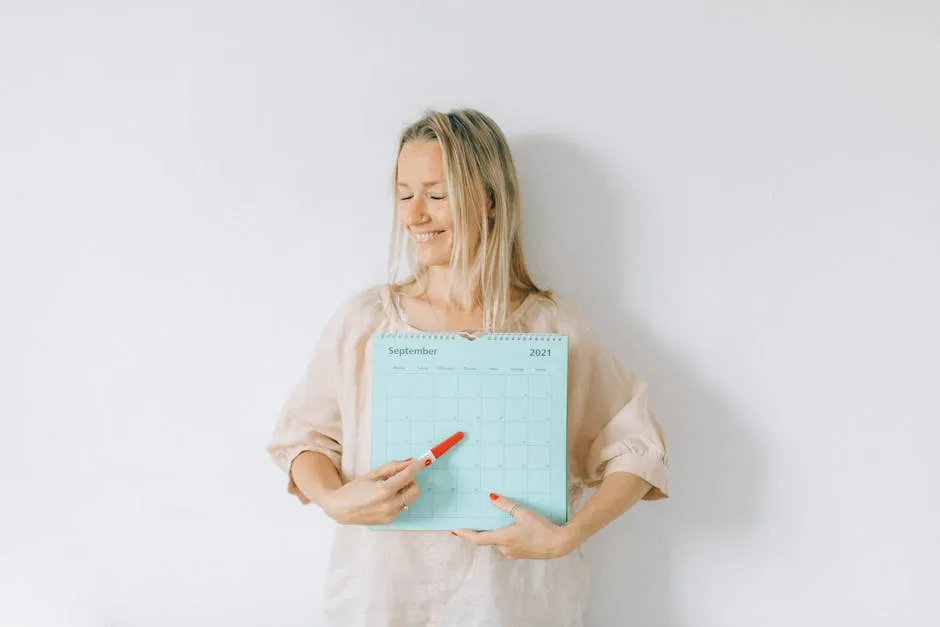 A Woman Pointing a Pregnancy Test at a Calendar