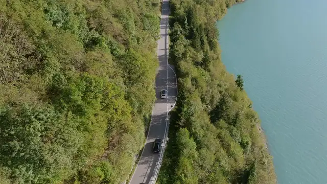 Horizontal video: Scenic aerial view of road by lakeside forest 28963715. Duration: 25 seconds. Resolution: 3840x2160