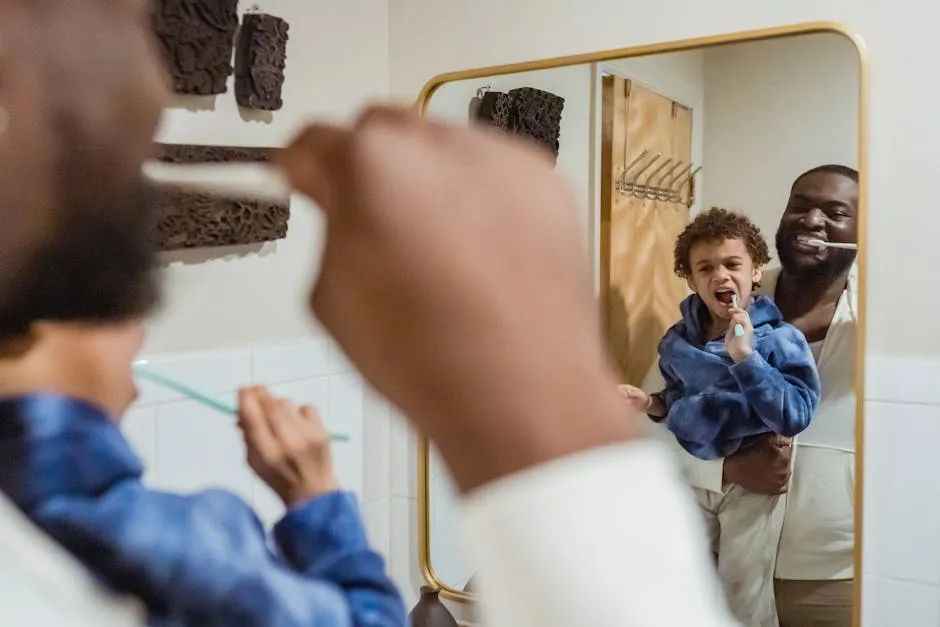 Positive African American male carrying cute son on hand and brushing teeth together against mirror in bathroom