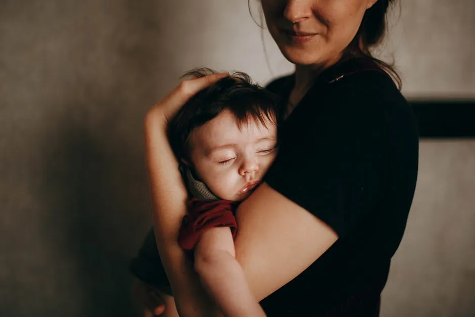 Crop mother with sleepy baby in arms