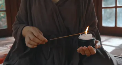 Horizontal video: Close up of a woman lighting an incense stick with a candle 11760296. Duration: 41 seconds. Resolution: 4096x2160