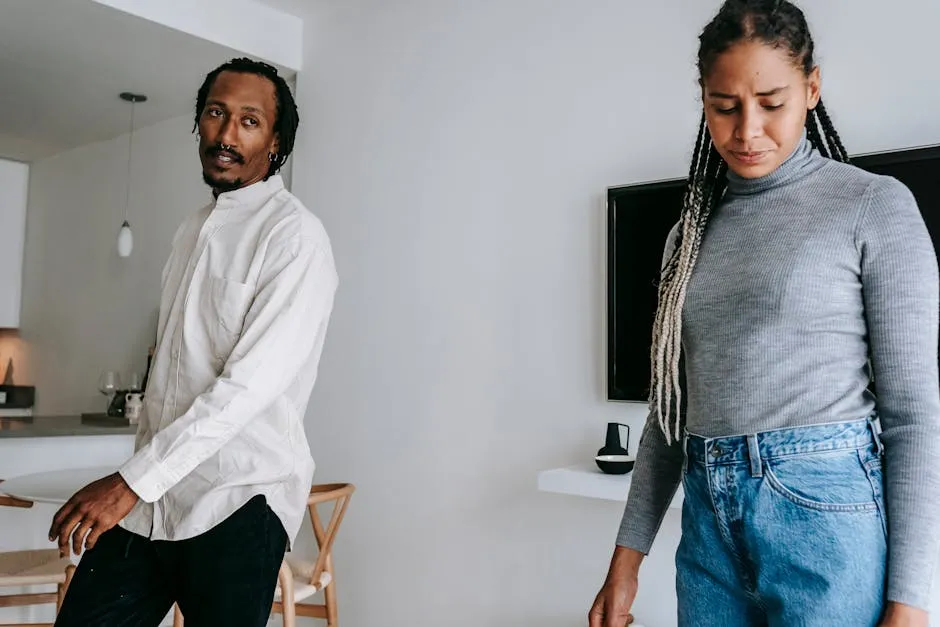 Concerned displeased African American couple in casual clothes having serious conversation in light living room