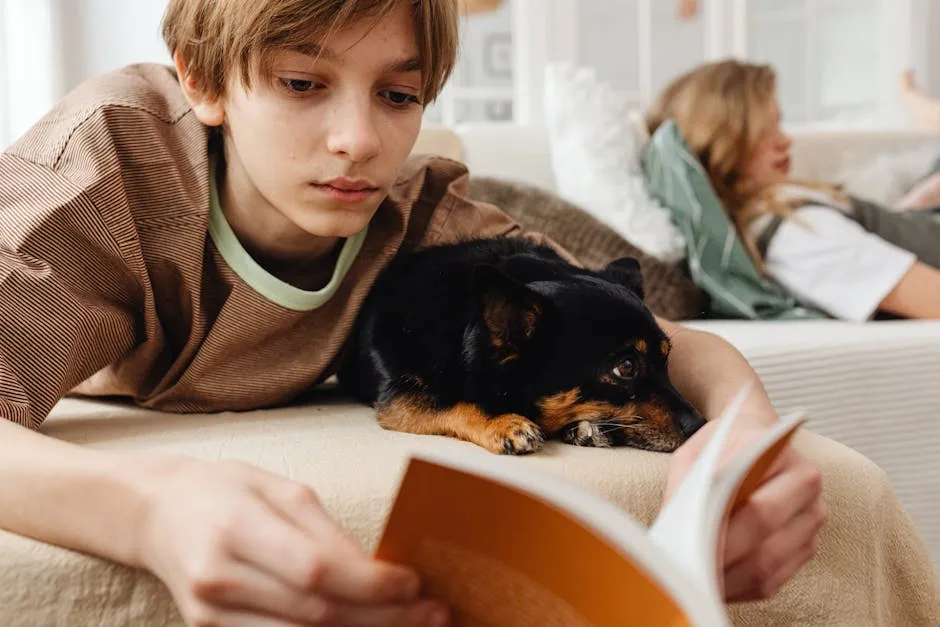 Close-up Shot of a Boy Lying on a Couch Beside His Pet Dog while Reading a Book