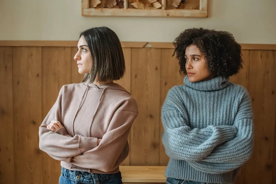 Unhappy African American woman in casual clothes with upset female standing in room with crossed arms while having conflict at home