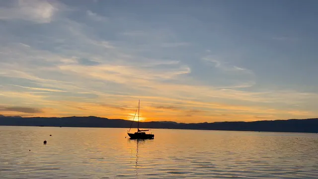 Horizontal video: Anchored boat at sunset on serene lake 29360158. Duration: 10 seconds. Resolution: 3840x2160