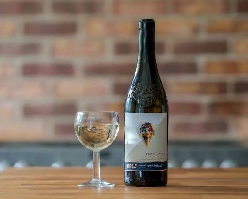 Elegant Pinot Grigio bottle and wineglass on a wooden table against a brick wall.