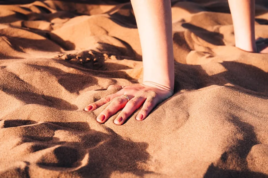 Hand Wearing Wedding Ring Touching Sand