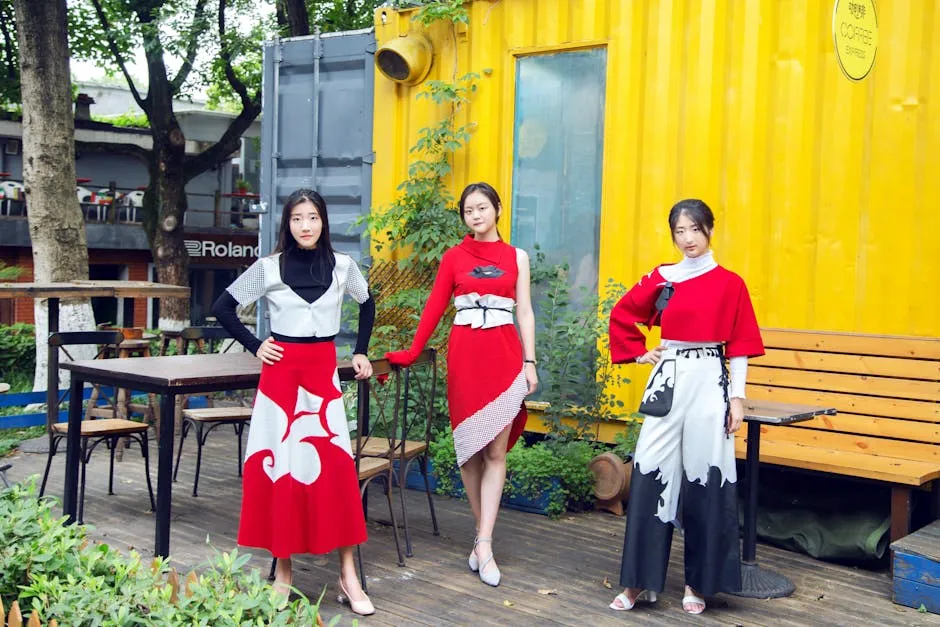 Three women in stylish red and black outfits pose outdoors against a yellow container backdrop.