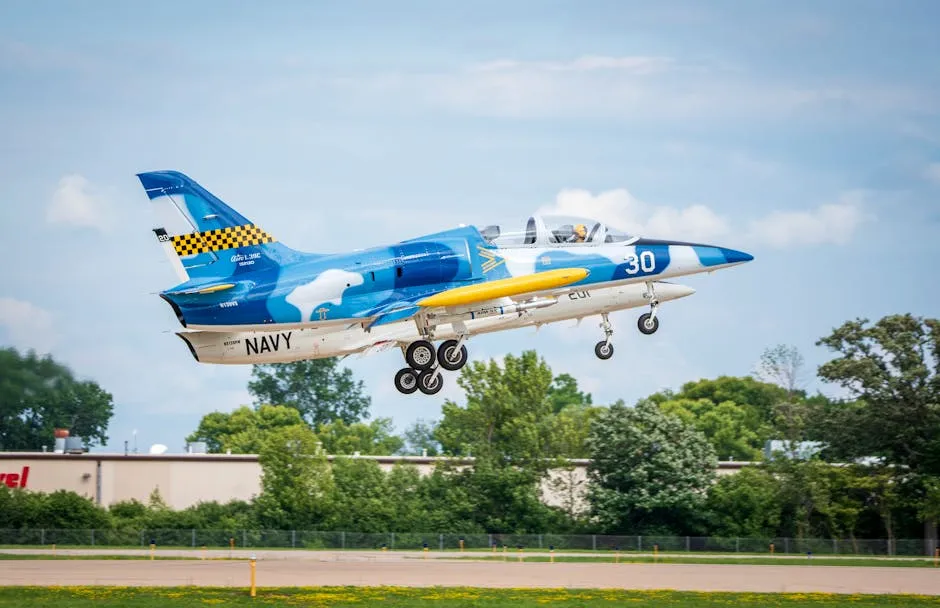 A vibrant blue and yellow Navy jet ascends over a runway surrounded by greenery.