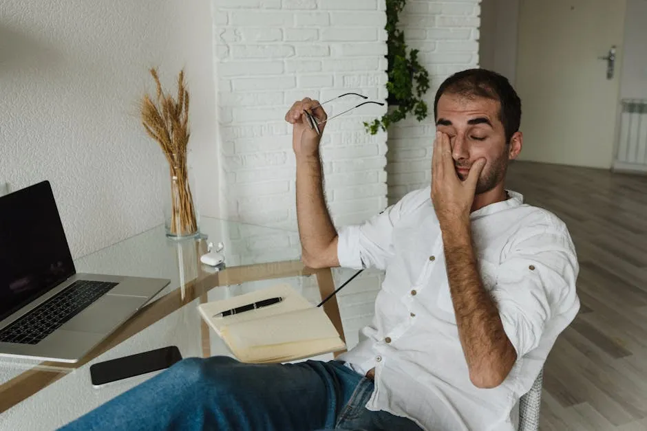 Man in White Dress Shirt Sitting on Chair Wiping Eyes