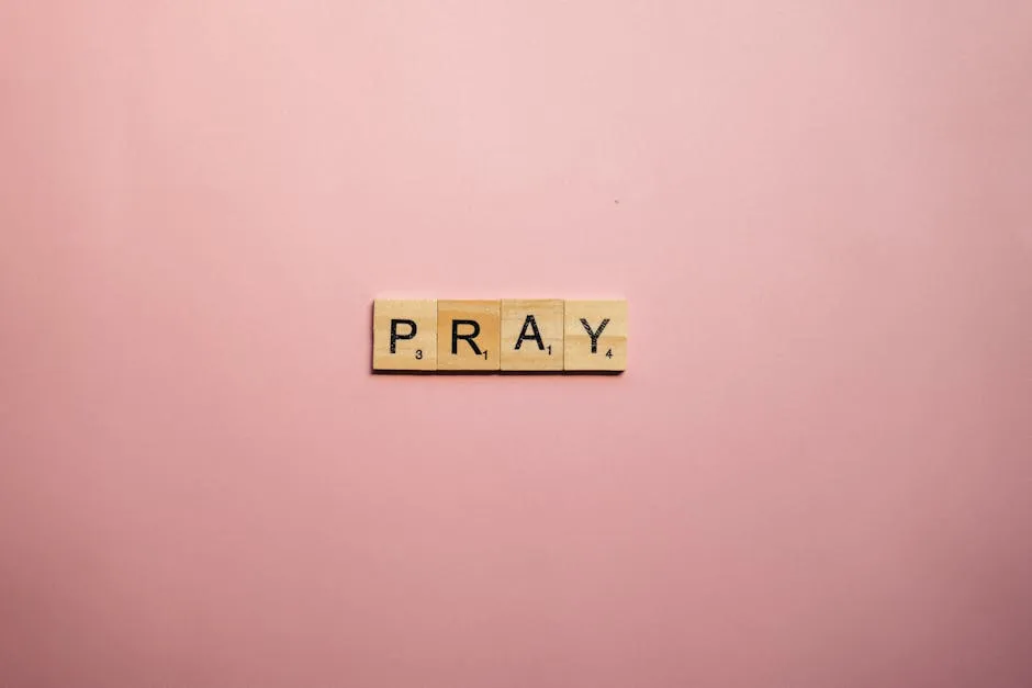 Scrabble tiles spelling 'Pray' on a pink surface offer a serene message.