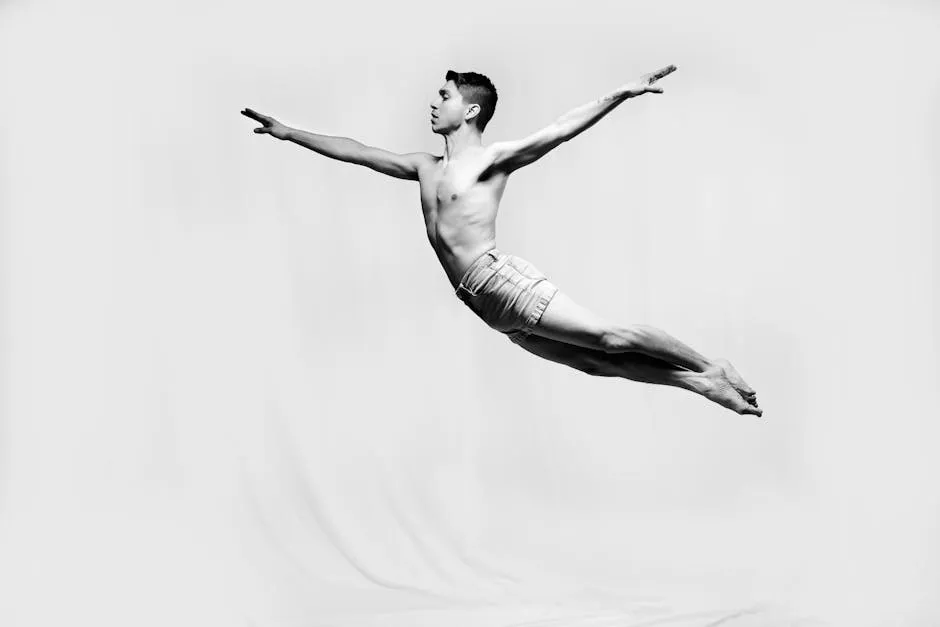 A captivating black and white photo of a male gymnast performing a dramatic leap, showcasing strength and grace.