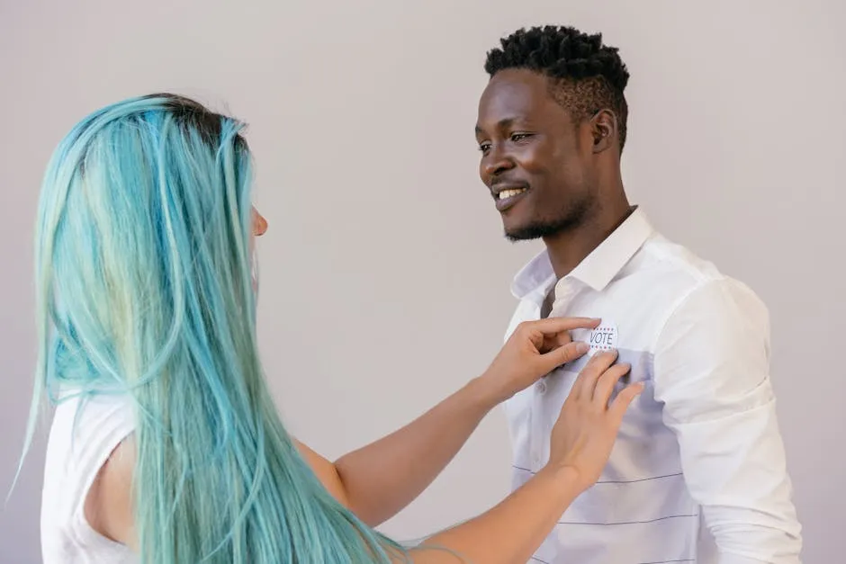 A woman pins a voting badge on a smiling man's shirt, promoting civic engagement.